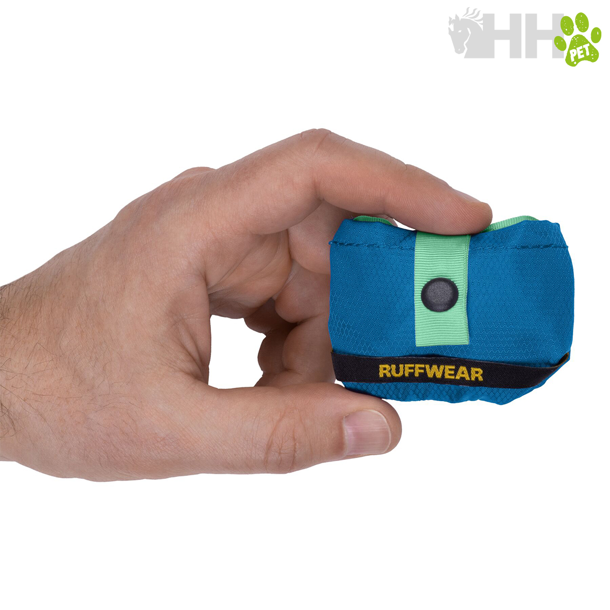 Dispensador de sacos de cão azul com detalhes verde e preto com a marca RUFFWEAR, segurado por uma mão