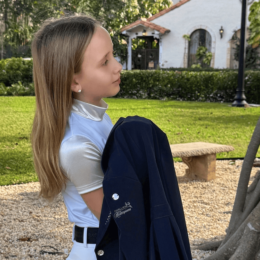 Menina com camisola prateada e casaco azul escuro com bordado ao ar livre