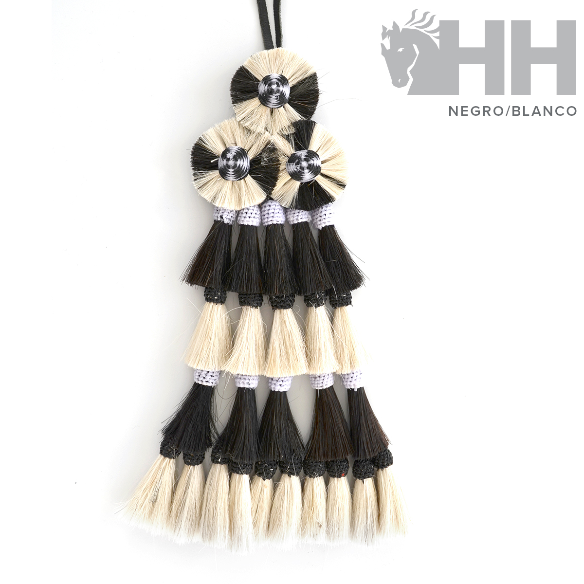 Pendente decorativo em franjas pretas e brancas em fundo branco.