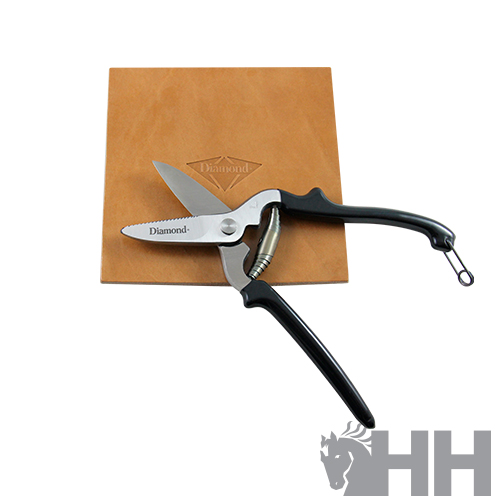 Tesoura preta com lâminas metálicas sobre suporte de couro castanho