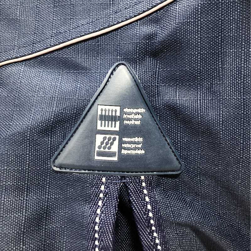 Etiqueta triangular preta com texto sobre tecido azul escuro