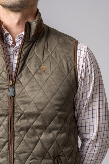 Colete verde-oliva matelassado com fecho de correr e bordado TC sobre camisa xadrez