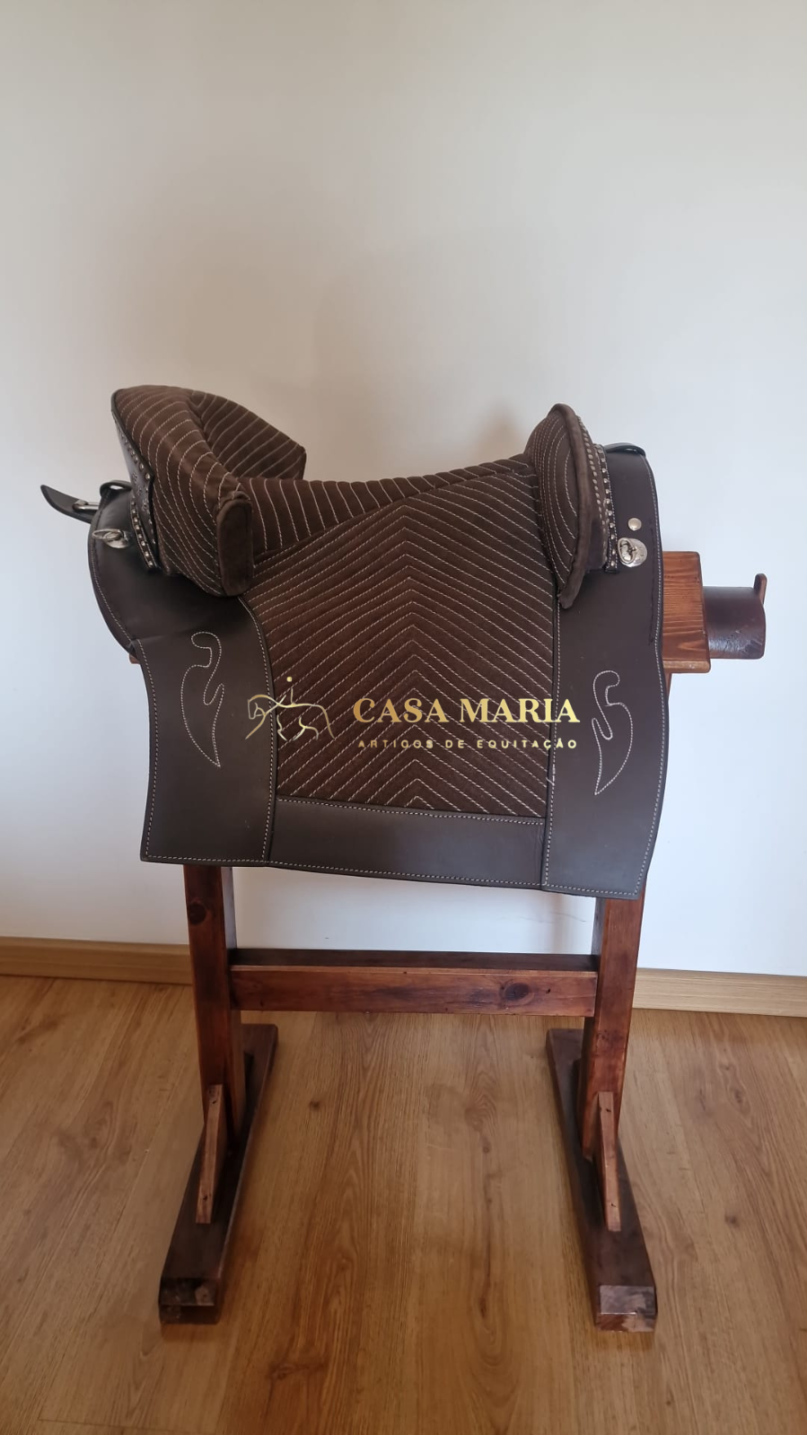 Sela de equitação castanha em suporte de madeira