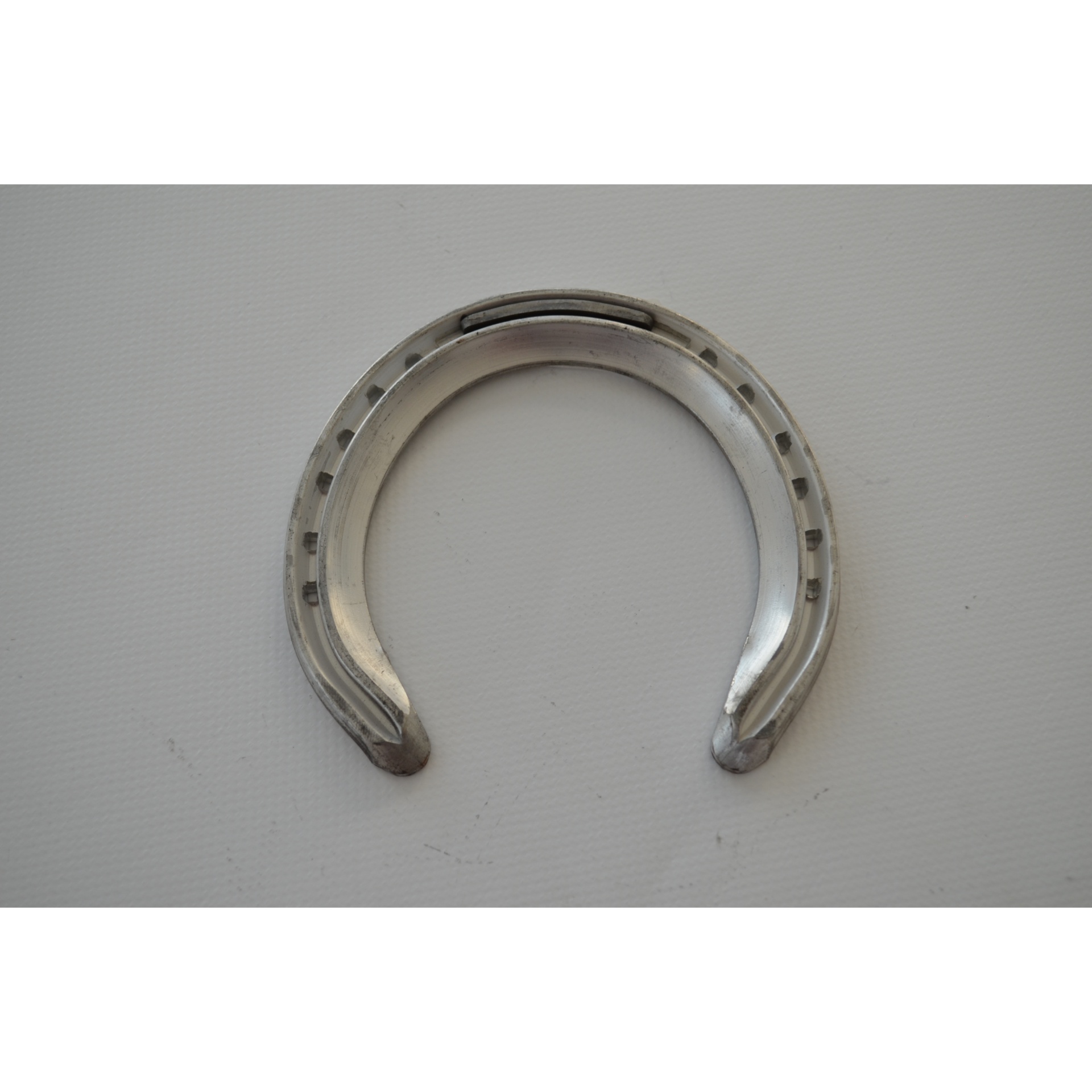 Ferradura metálica prateada com orifícios para pregos