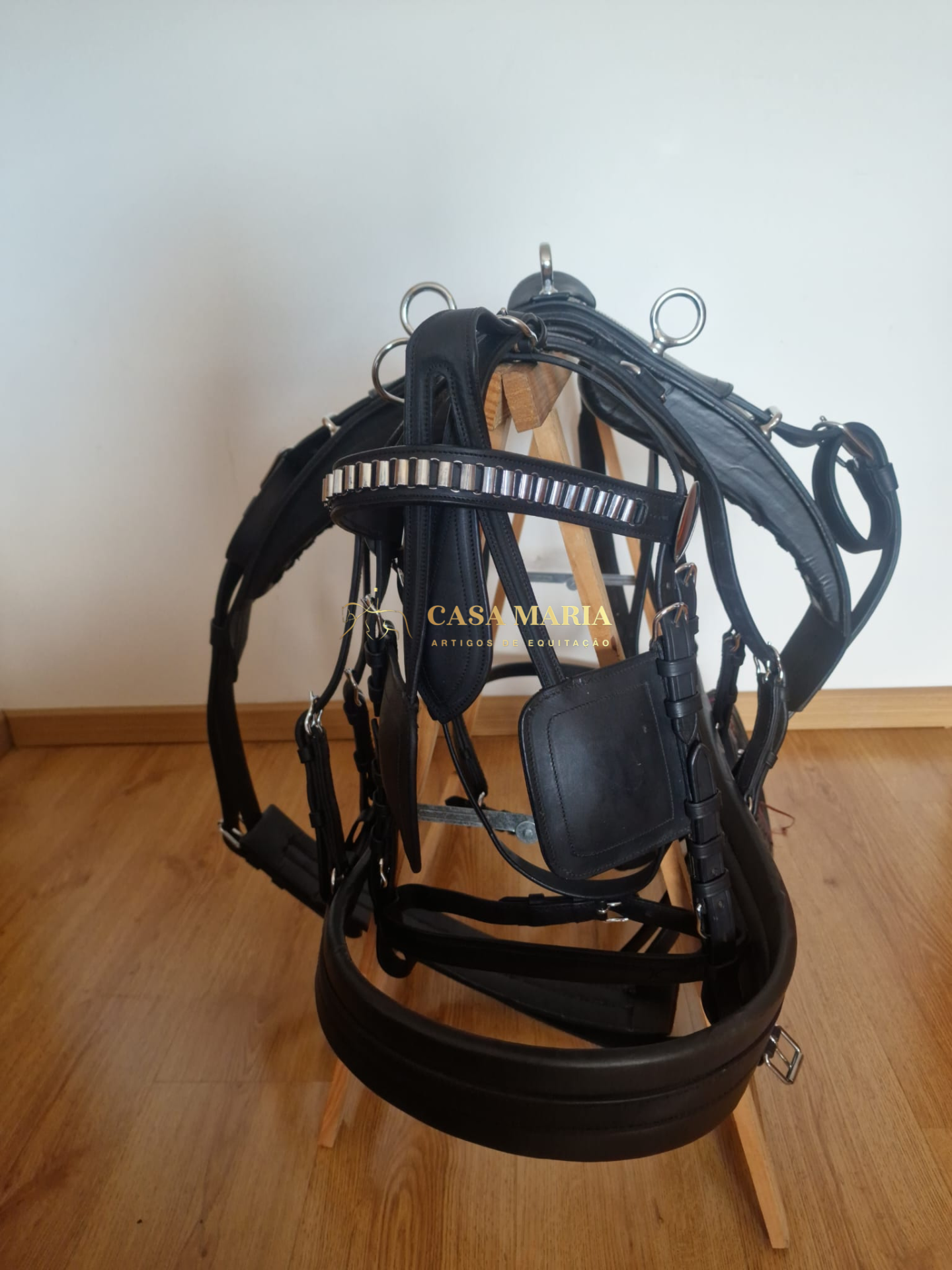Bridão e peitoral preto de couro com metal prateado em suporte de madeira