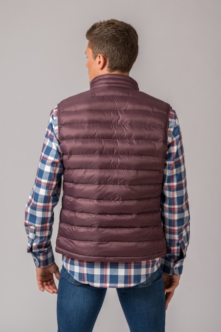 Colete acolchoado castanho visto de trás, usado com camisa xadrez e jeans.