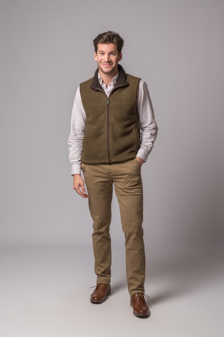 Homem com colete castanho, camisa xadrez clara, calças bege e sapatos castanhos