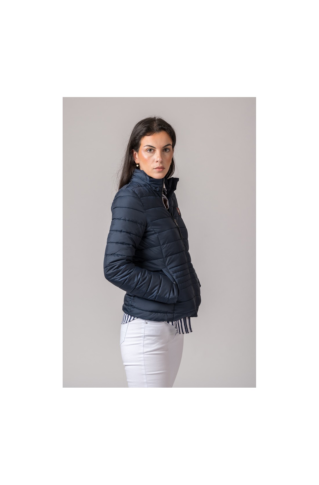 Casaco acolchoado azul escuro com fecho e bolsos, visto de lado