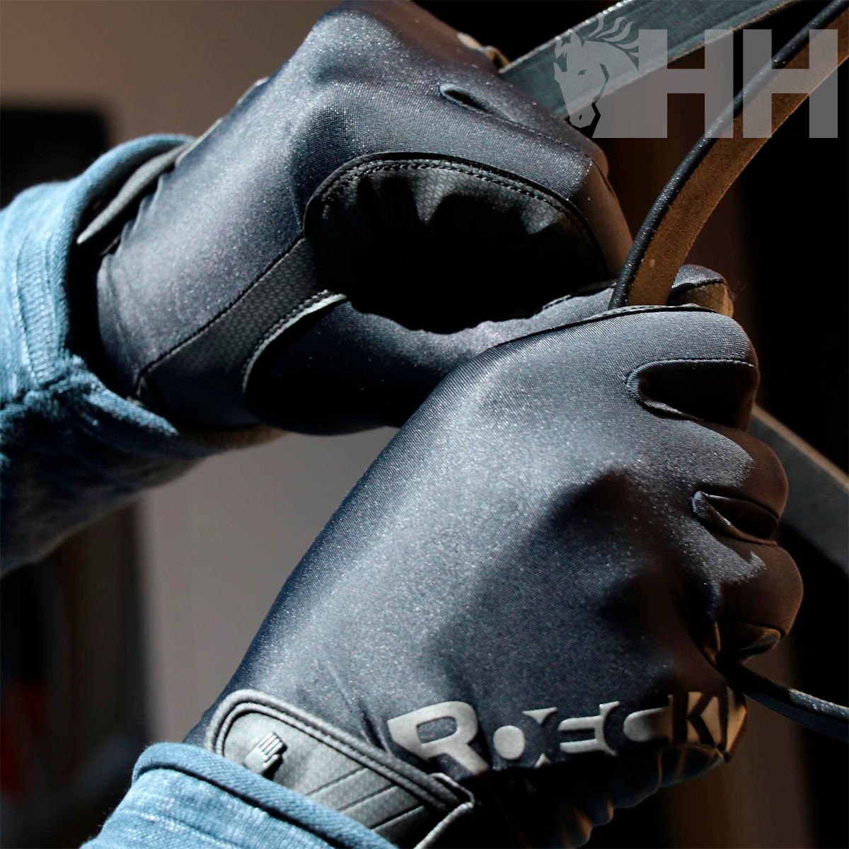 Luvas pretas com texto ROECKL a segurar uma correia preta