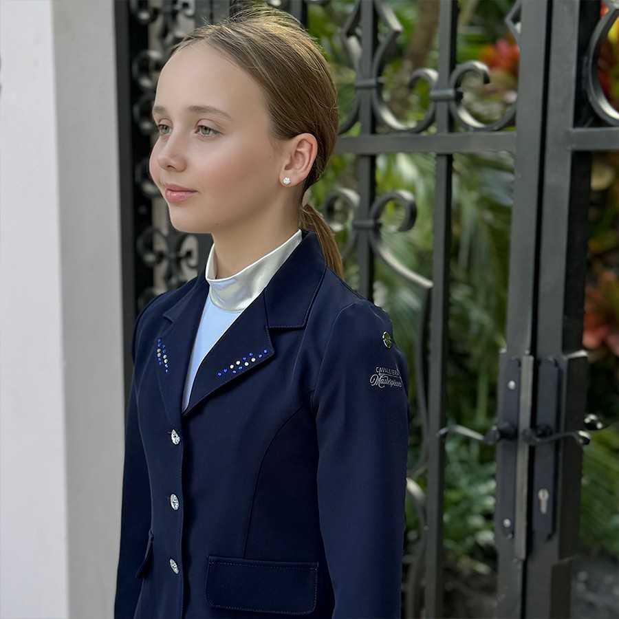 Menina a usar blazer azul escuro com botões e strass, junto a portão preto