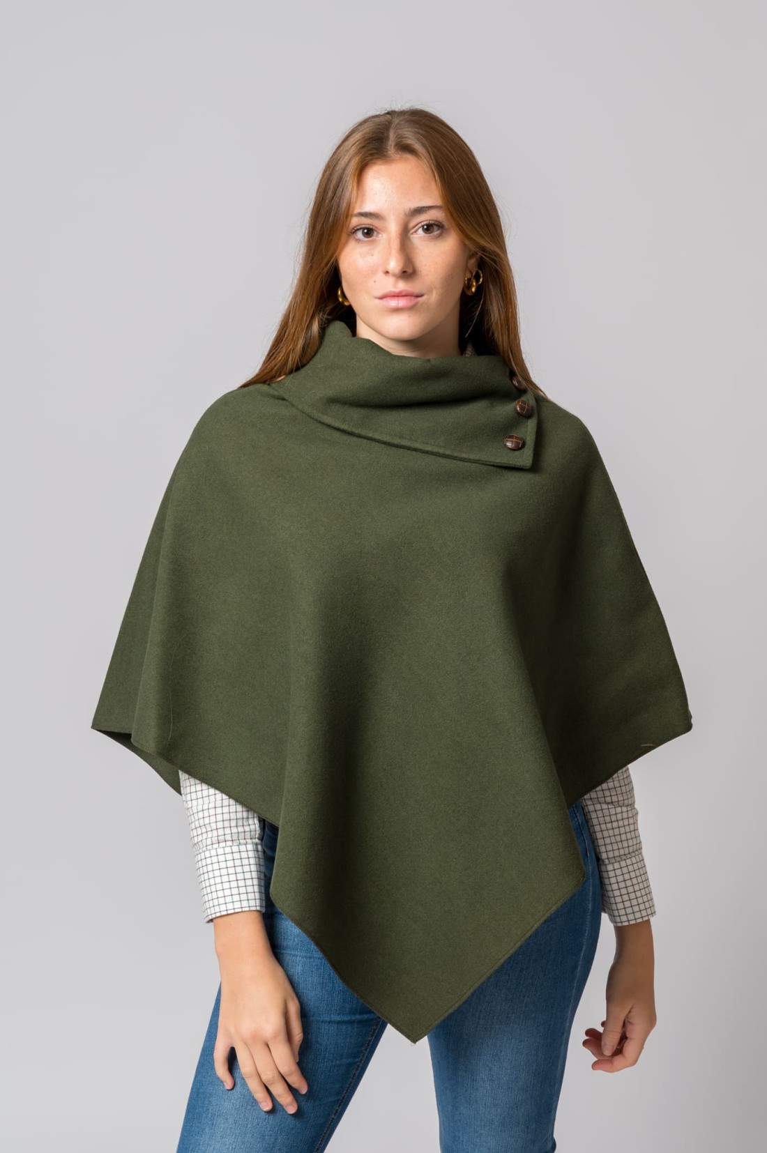 Mulher vestindo poncho verde com botões e camisa branca com padrão de quadrados.