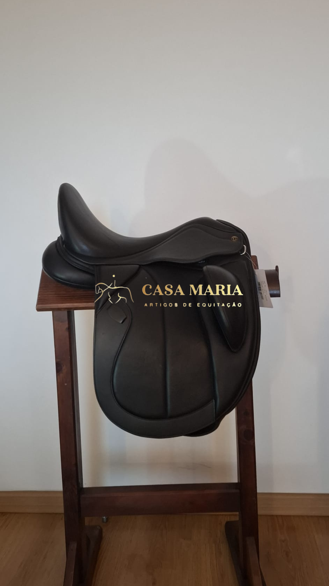 Sela preta de equitação em couro num suporte de madeira