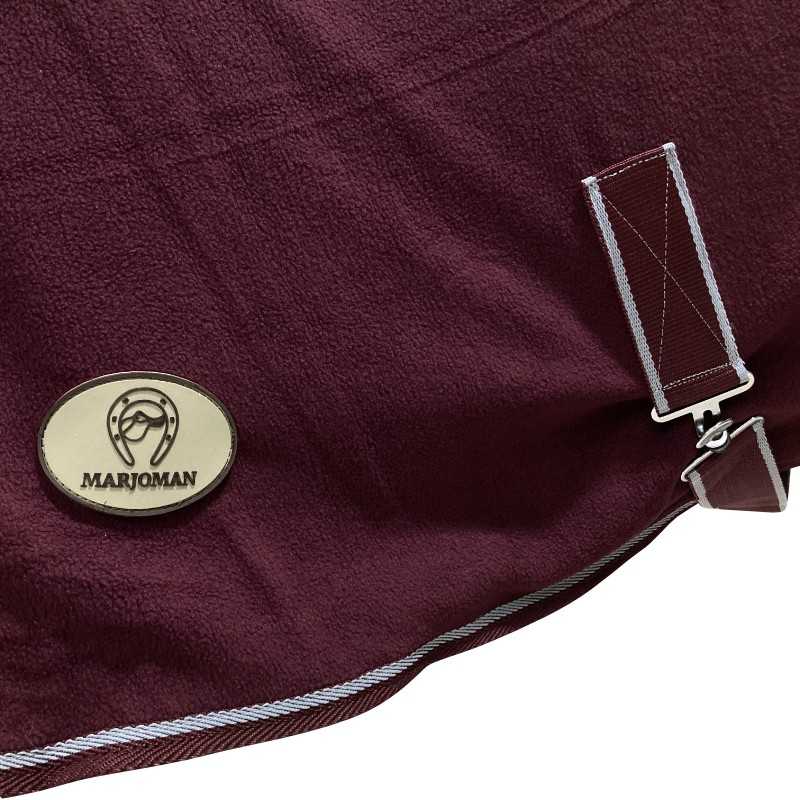 Cobertor tecido polar vinho com bordas brancas, fivela metálica e etiqueta MARJOMAN