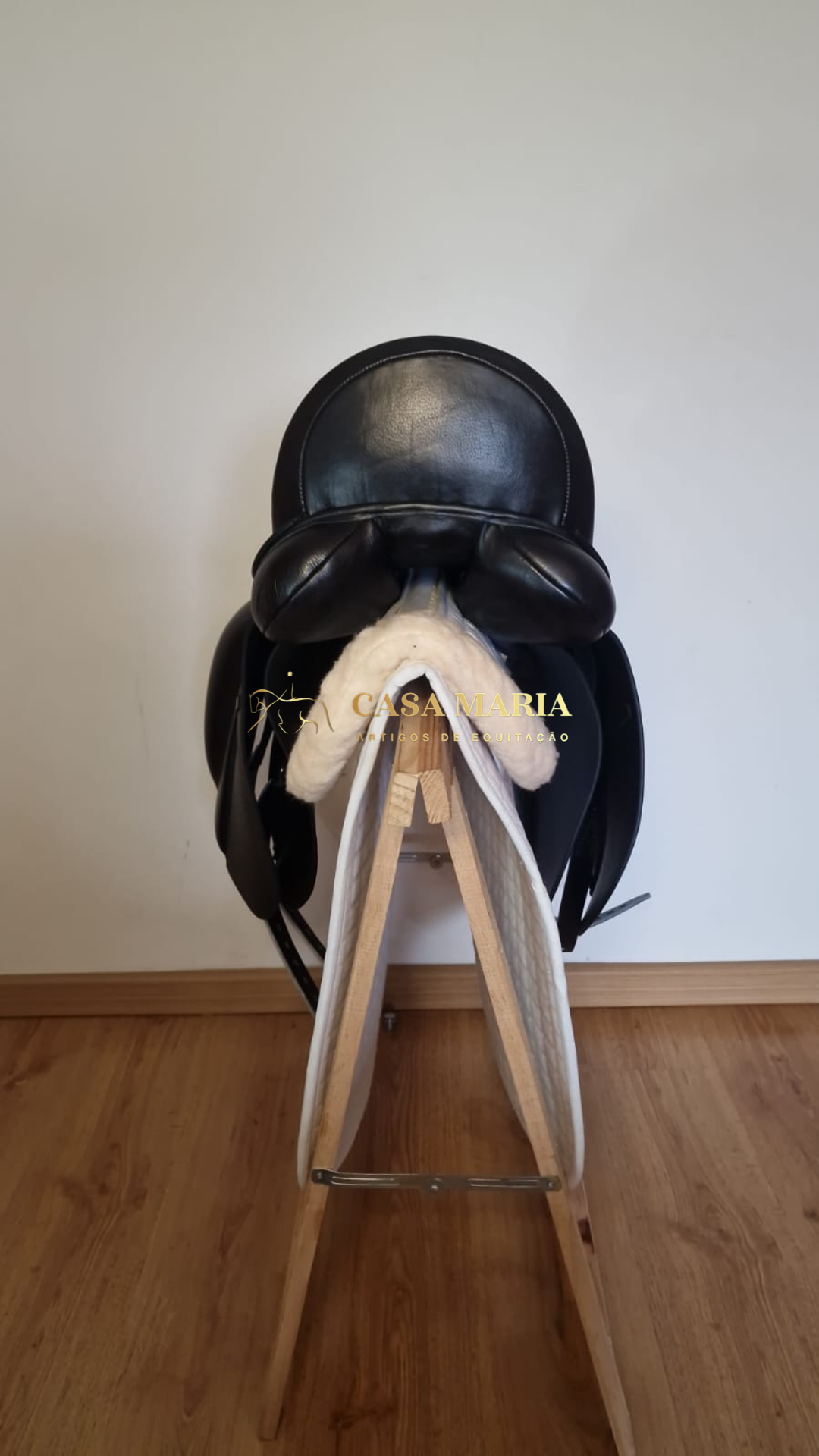 Sela preta de couro sobre suporte de madeira com forro acolchoado branco