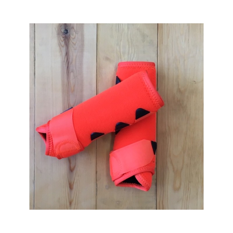 Joalheiras ou cotoveleiras de neopreno laranja com detalhes pretos sobre madeira clara