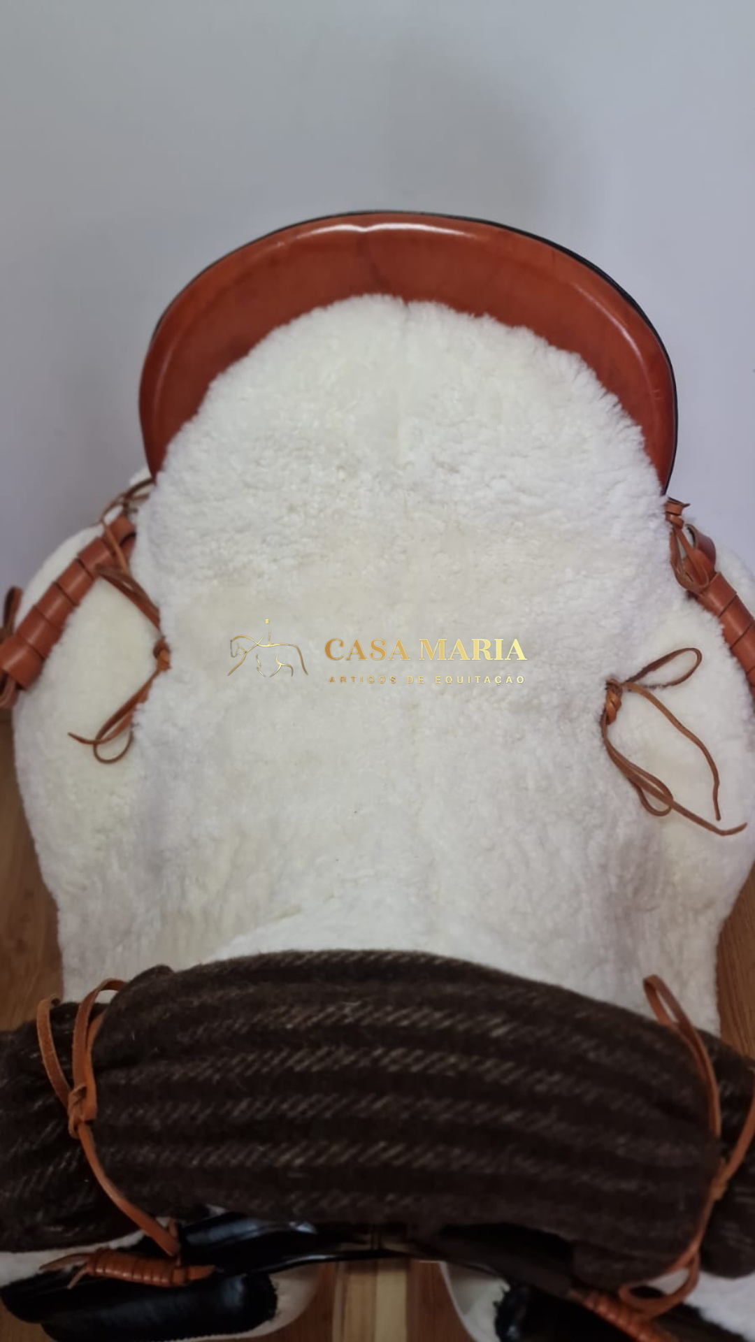 Sela de equitação com assento branco felpudo e detalhes castanhos