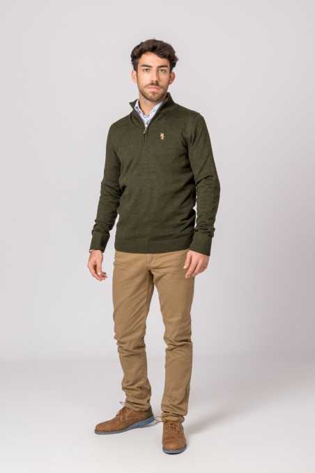 Homem com camisola verde, calças castanhas e sapatos castanhos em fundo branco