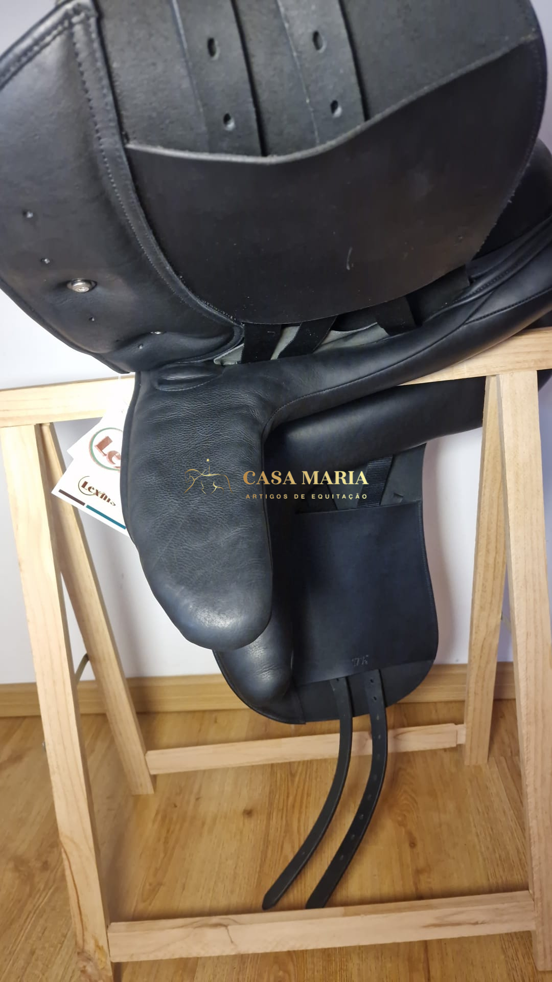 Sela de equitação preta em couro sobre suporte de madeira