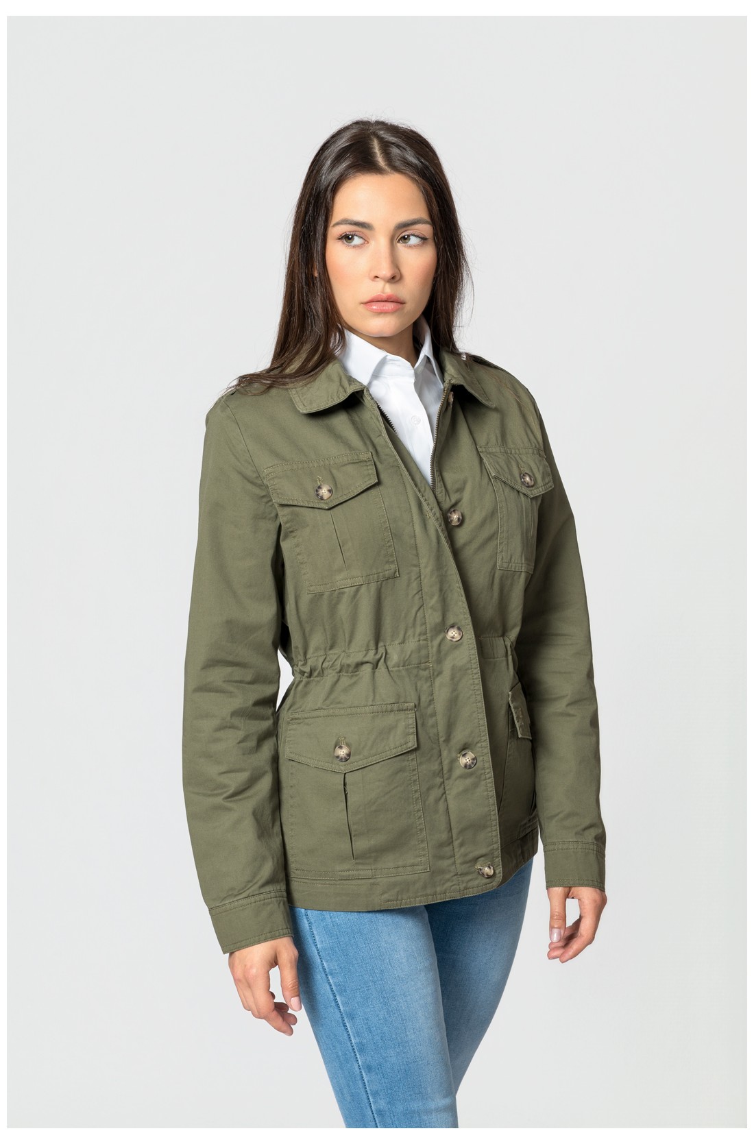 Mulher a usar casaco verde militar, camisa branca e jeans azul-claro