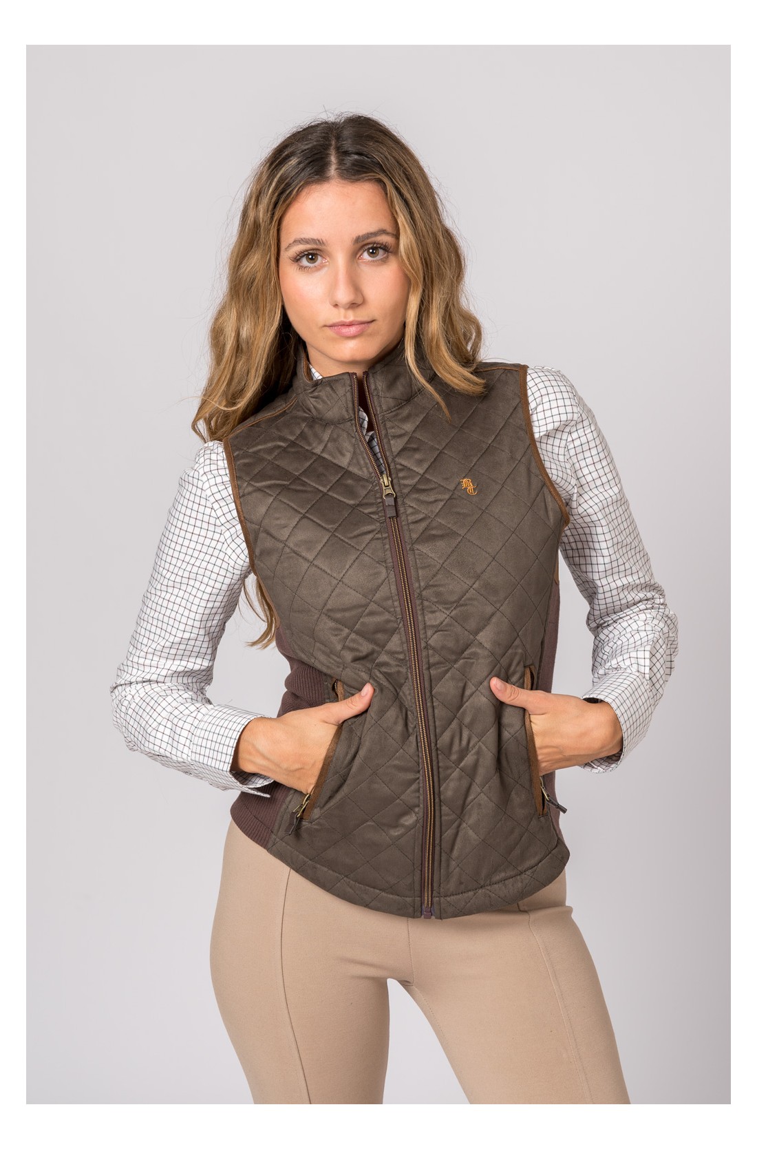 Colete acolchoado castanho feminino com fecho, usado sobre camisa xadrez