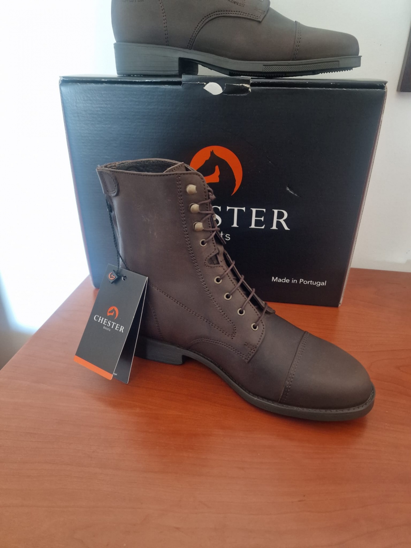 Botas de couro castanho da marca Chester sobre caixa preta