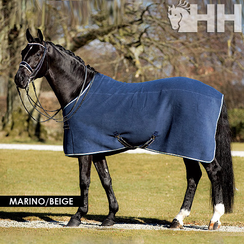 Cavalo preto com manta azul-marinho e beje junto a árvore exterior