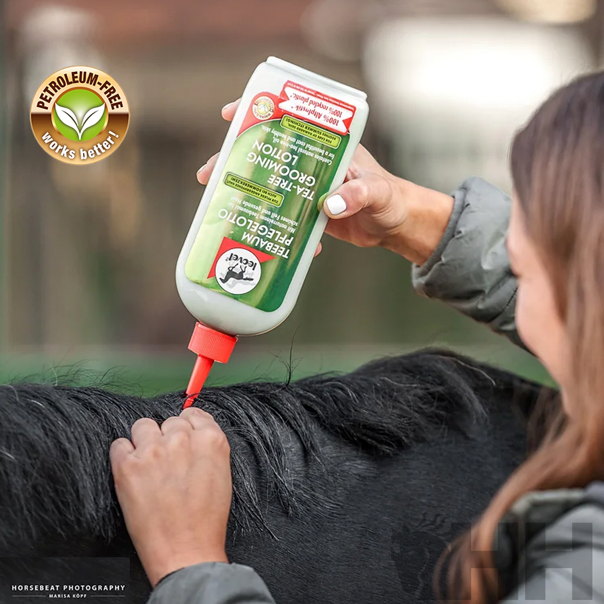 Frasco branco com rótulo verde aplicado no pelo de um cavalo preto por uma pessoa.