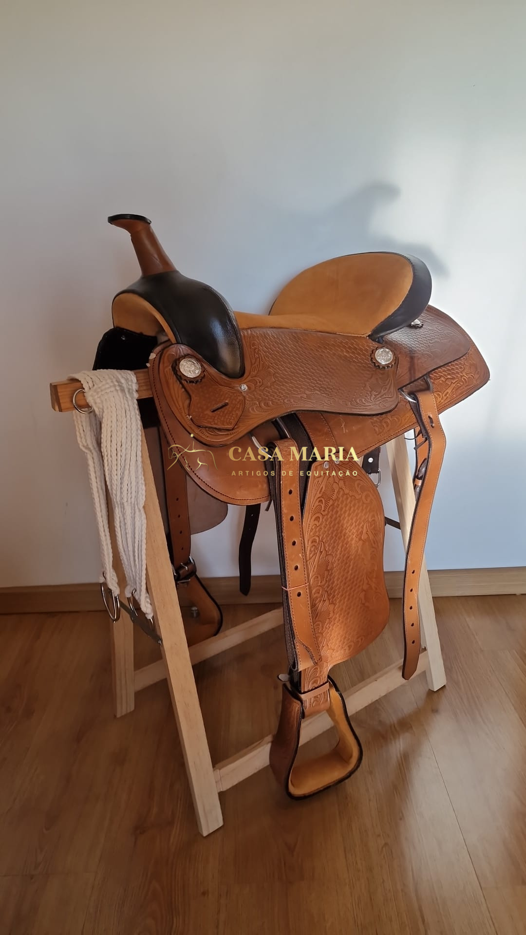 Sela de couro castanho em suporte de madeira com cabresto branco