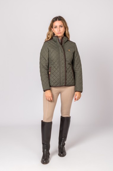 Mulher vestindo casaco verde acolchoado, calças bege e botas pretas em fundo branco.