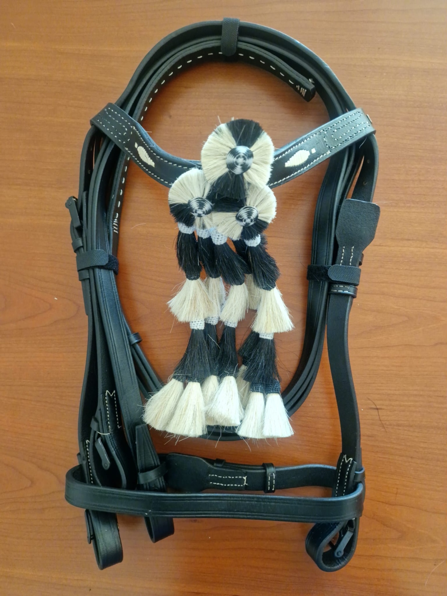 Cabresto de couro preto com cordões trançados preto e creme sobre superfície de madeira