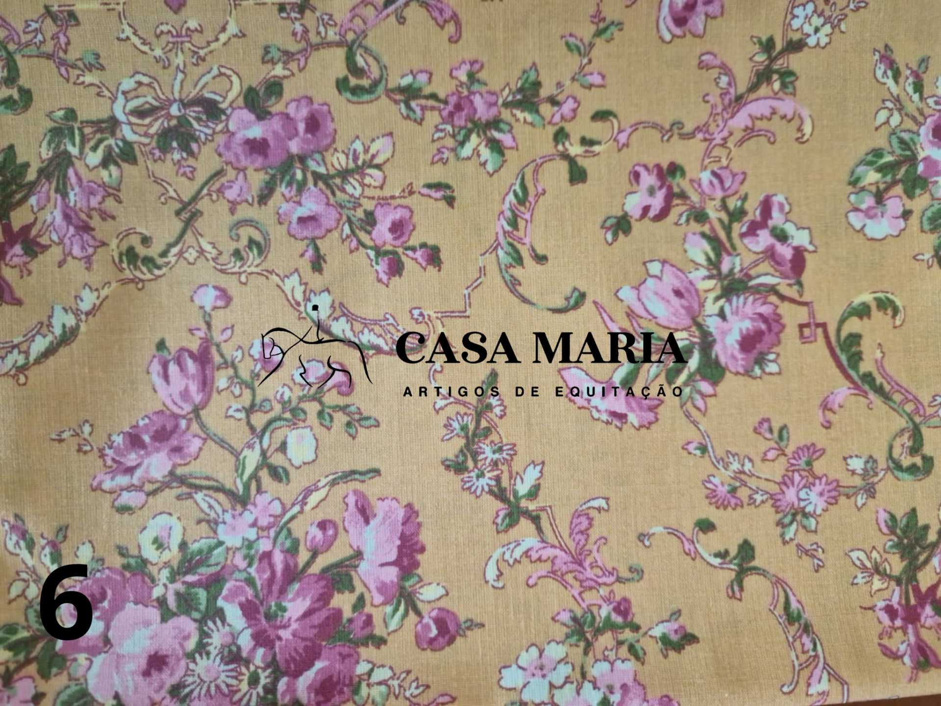 Tecido floral amarelo mostarda com padrão em rosa, roxo, branco e verde e texto impresso