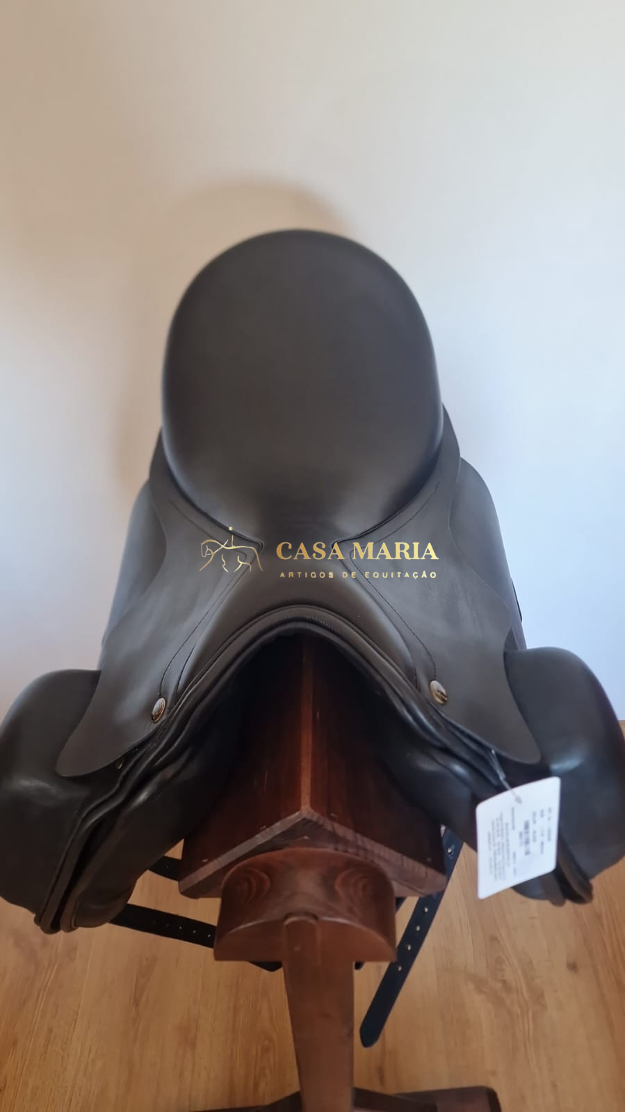 Sela de equitação preta em couro numa estrutura de madeira