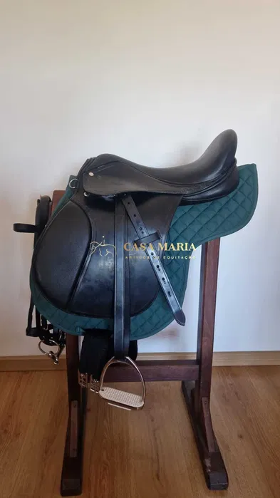 Sela preta de equitação em suporte de madeira com acolchoado verde