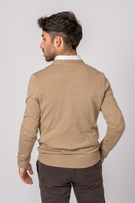 Homem de costas com camisola bege, camisa branca e calças castanho-escuras