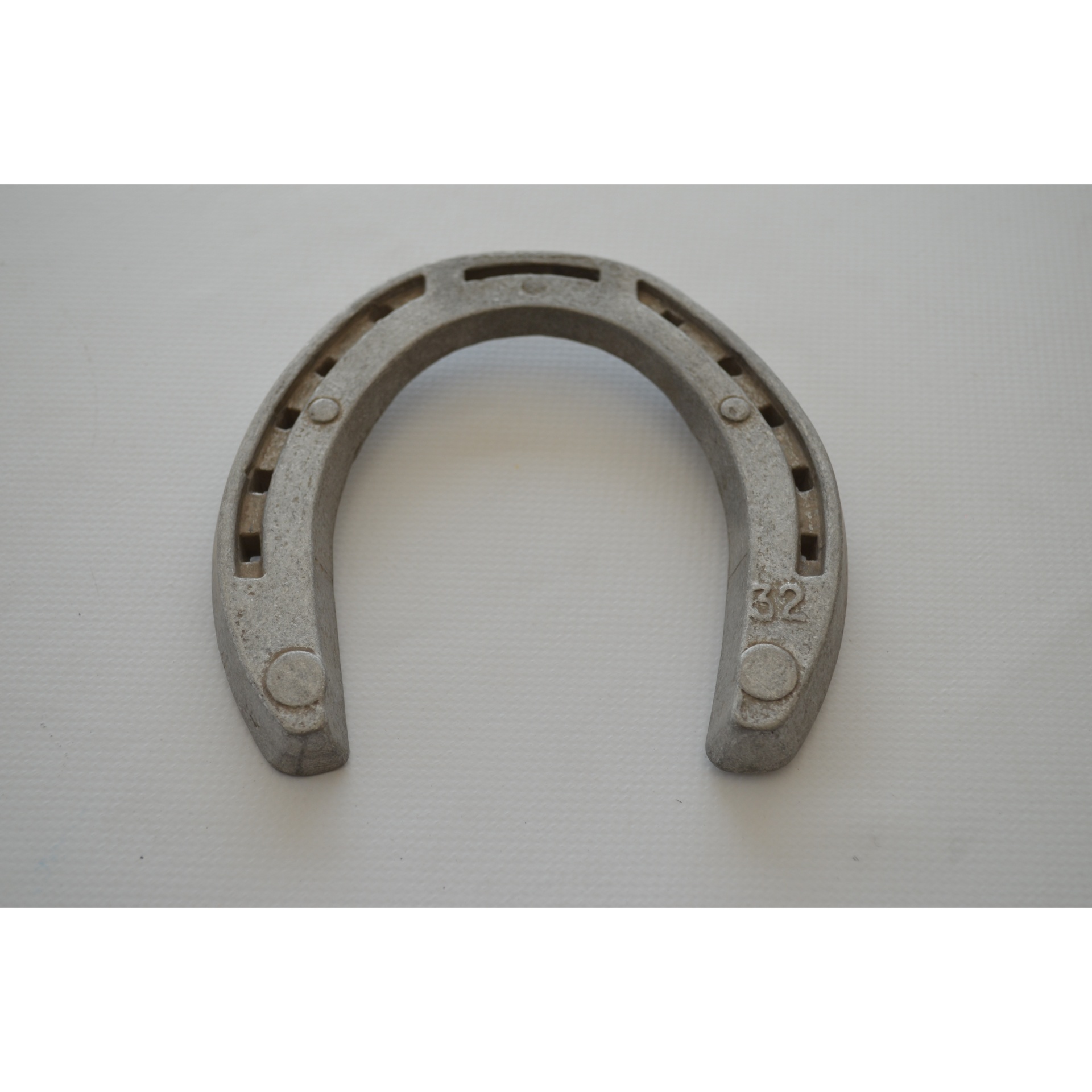 Ferradura metálica cinzenta com orifícios para pregos