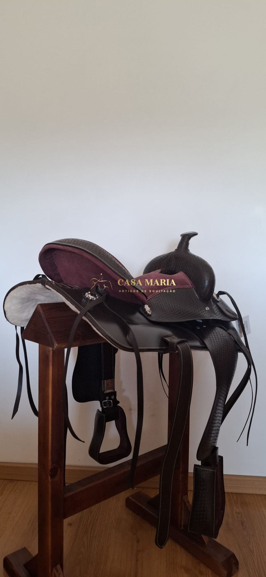 Sela de equitação castanha com estofamento vermelho numa cavalo de madeira