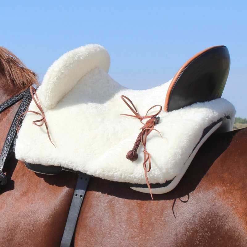 Sela de cavalo com almofada branca de pelo sintético sobre cavalo castanho