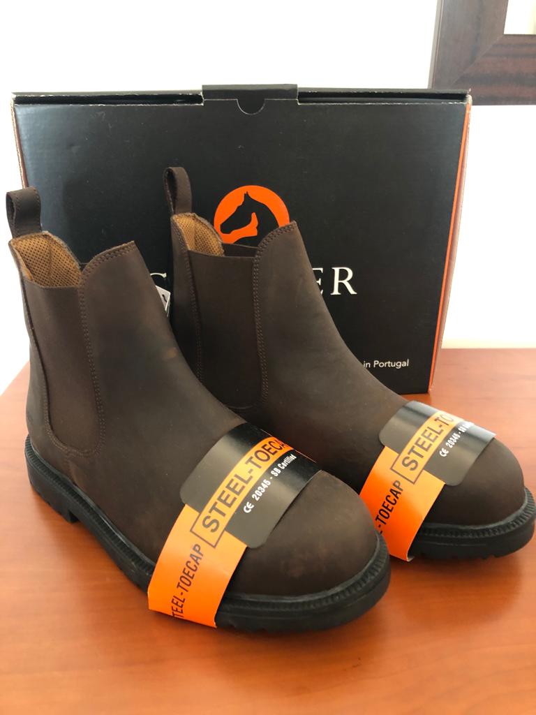 Botas de segurança marrons com etiqueta laranja e caixa preta com logotipo