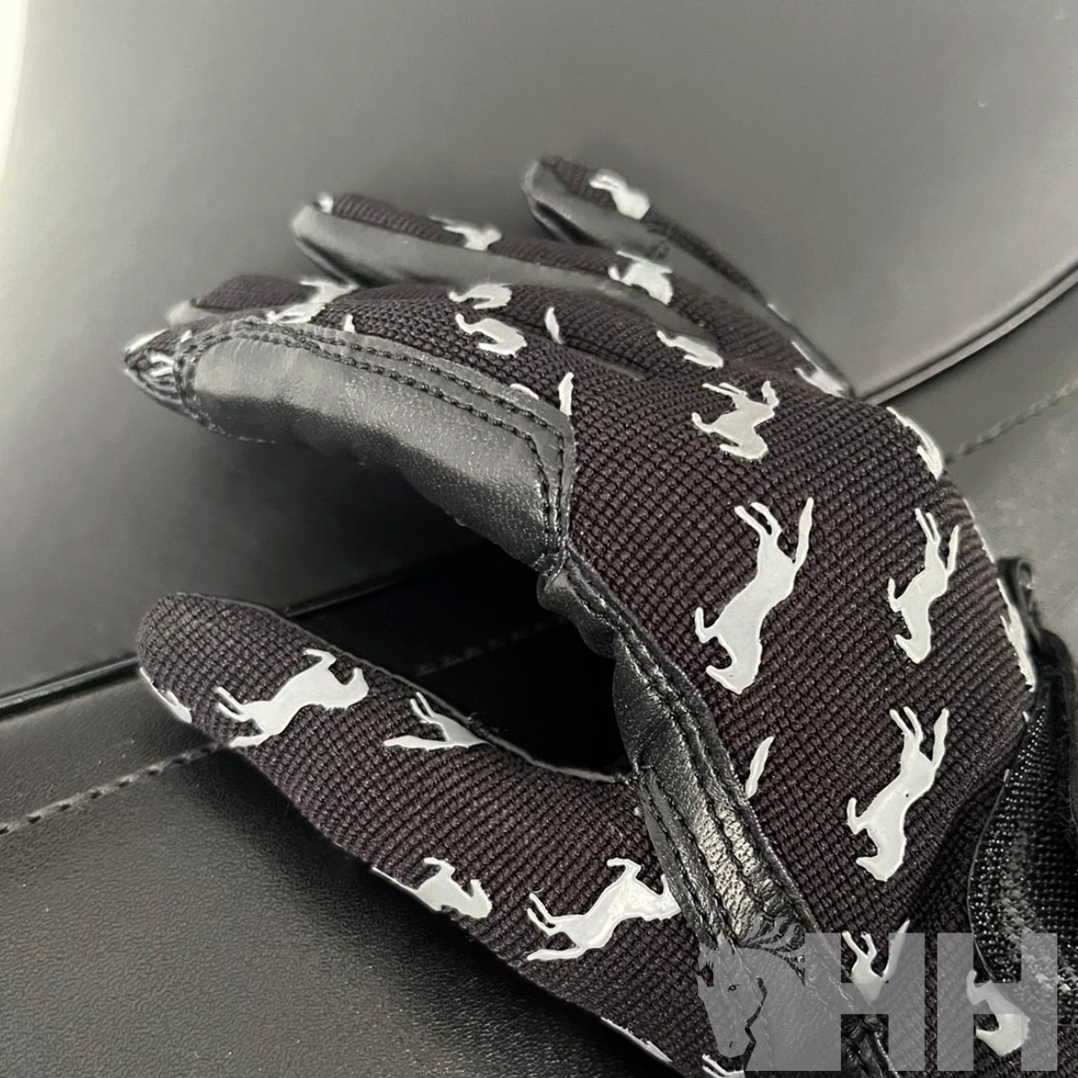 Luvas negras com padrão de cavalos brancos sobre superfície preta