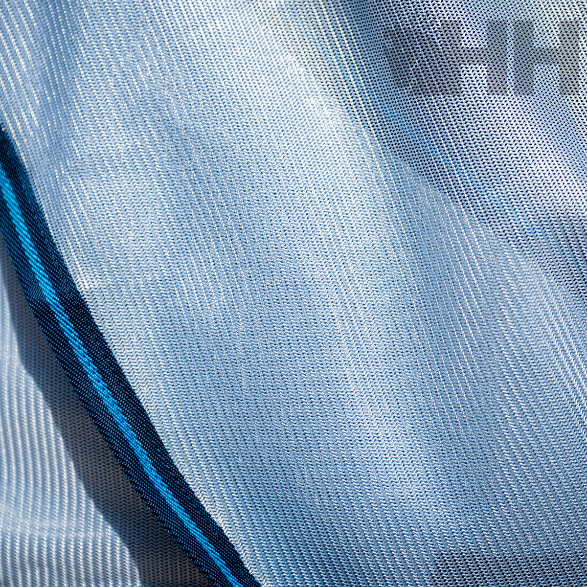 Tecido azul claro com faixa azul escura e preta e texto parcial 