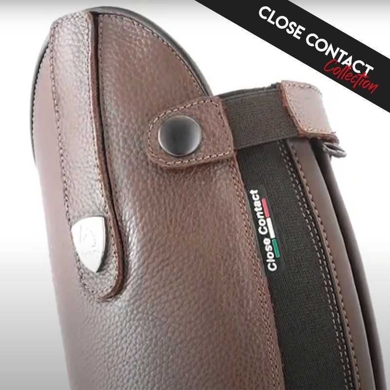 Equipamento de equitação em couro castanho com fecho elástico preto e texto Close Contact Collection