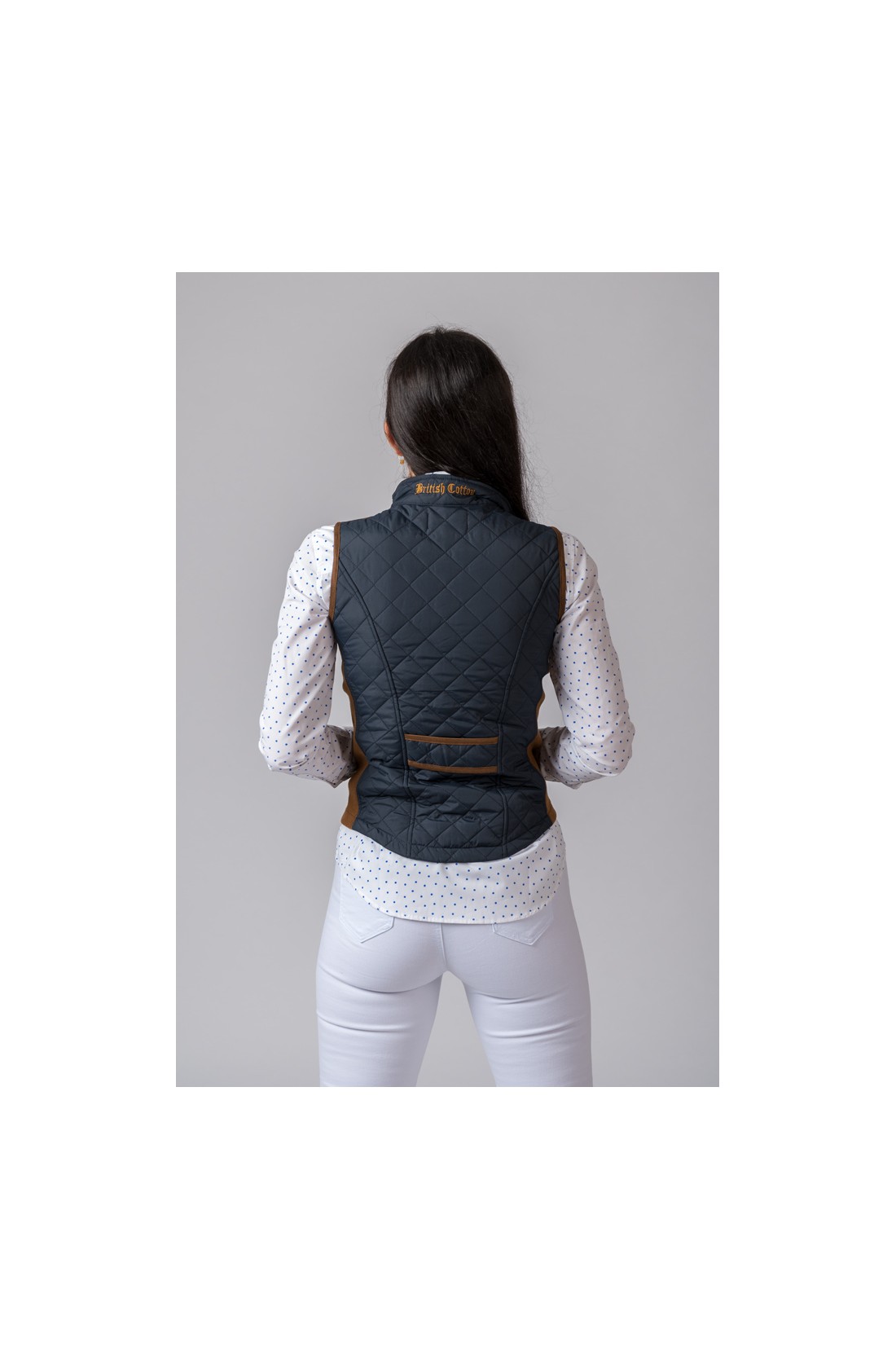 Colete azul escuro acolchoado com detalhes castanhos visto de costas.