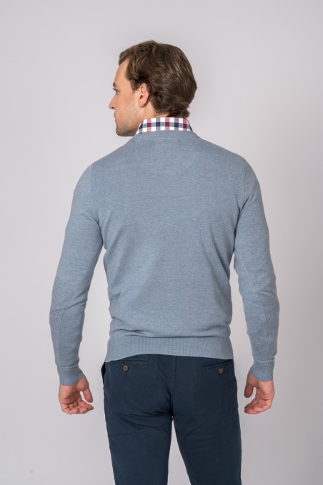 Homem de costas com camisola cinzento-azulada, camisa xadrez e calças azuis escuras