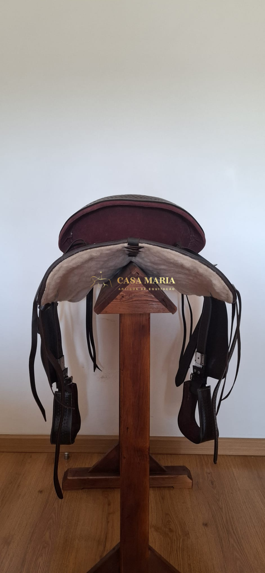 Sela de equitação castanha em suporte de madeira com interior forrado em pelo sintético