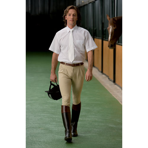 Homem com roupa de equitação a caminhar num estábulo com cavalo ao fundo