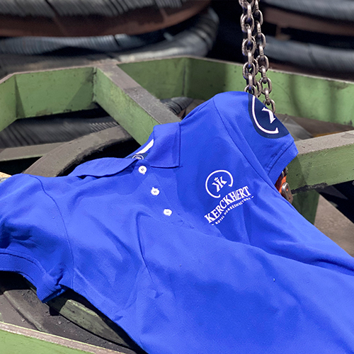 T-shirt polo azul com logos brancos em ambiente industrial