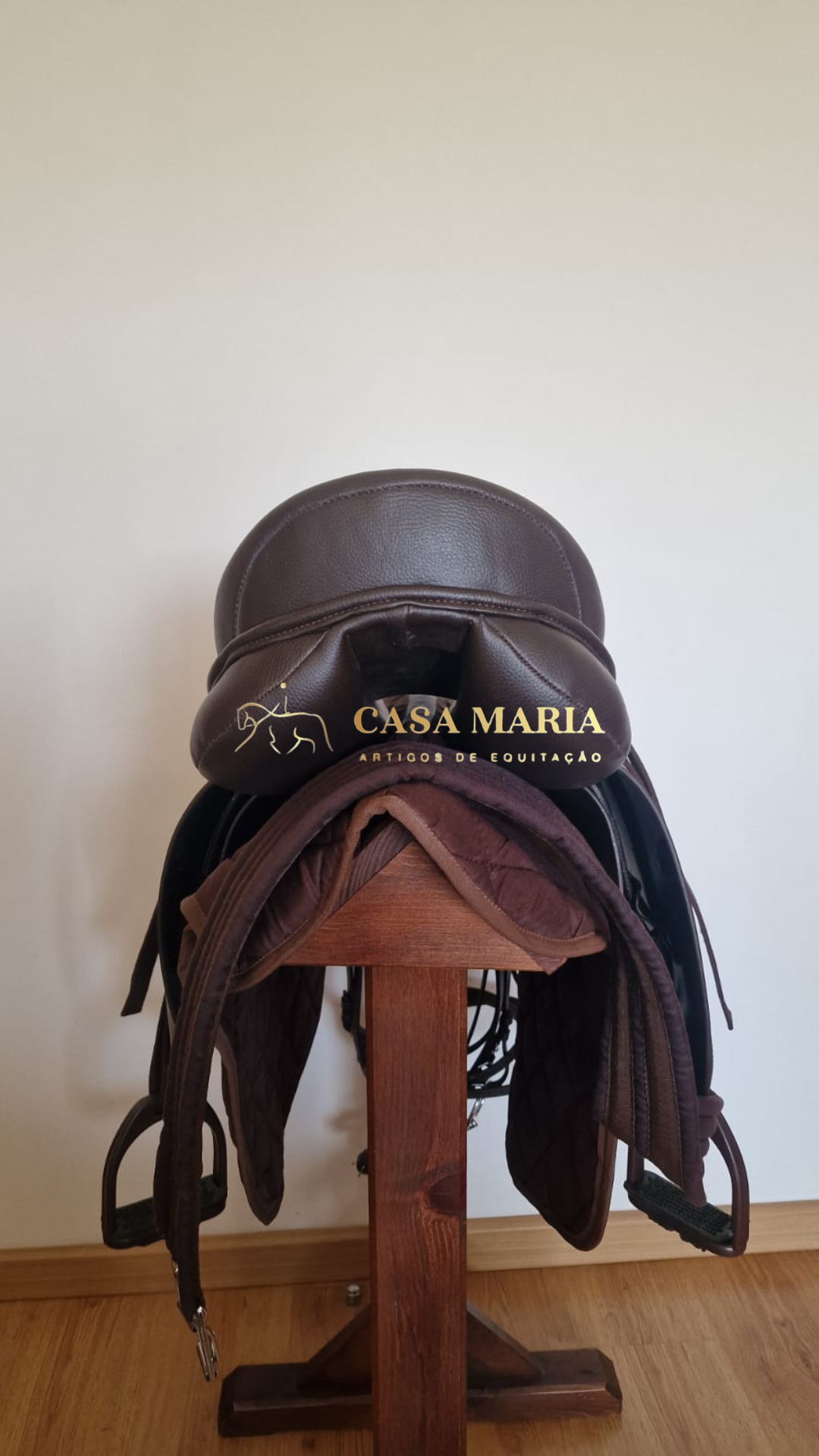 Sela de equitação castanha escura em suporte de madeira com texto da marca