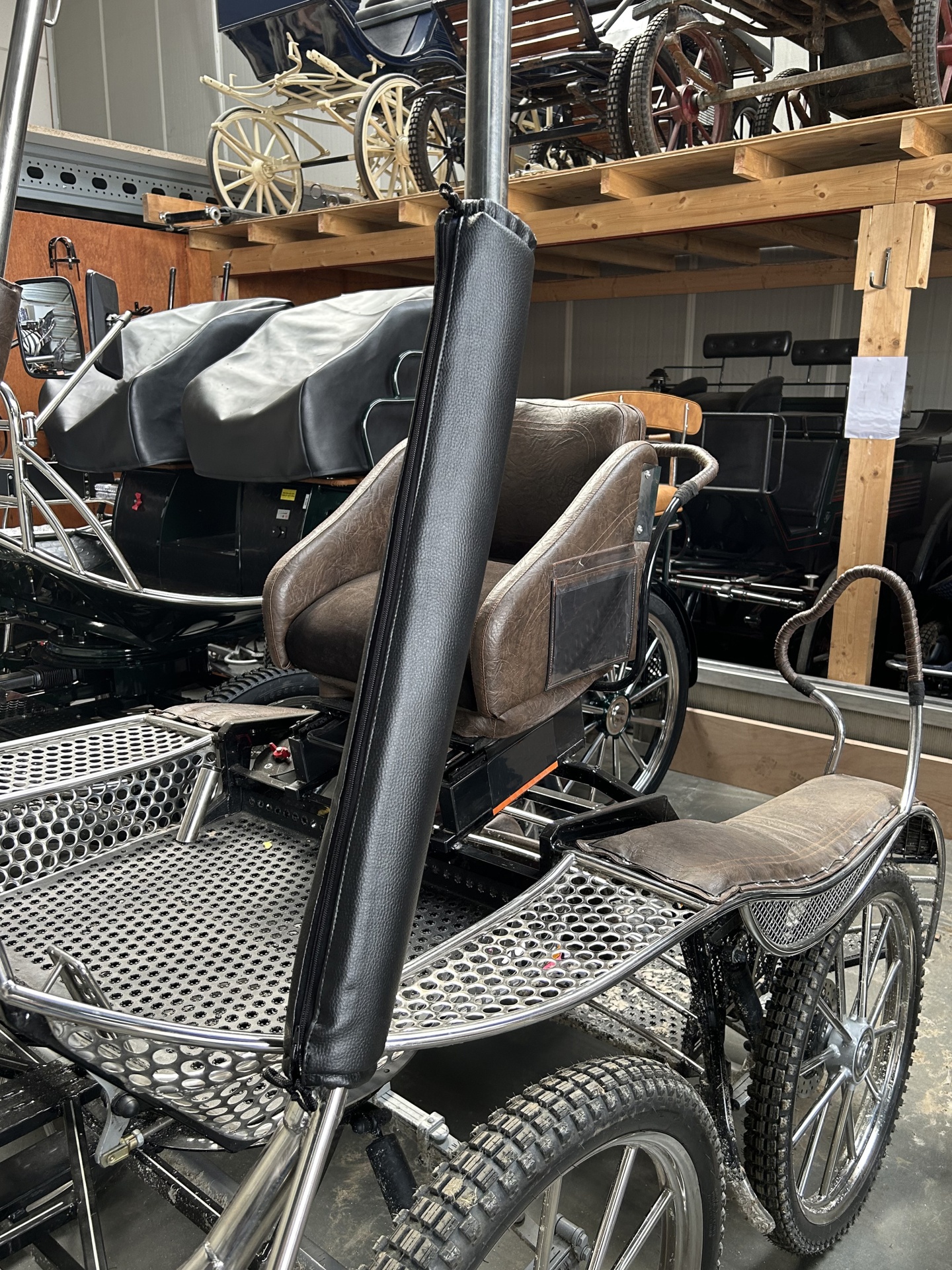 Cadeira de carruagem de metal e couro com rodas de borracha em armazém