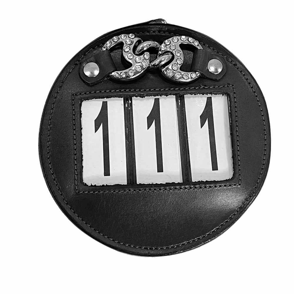 Bolsa redonda preta com alça de metal e pedras e número 111 visível.