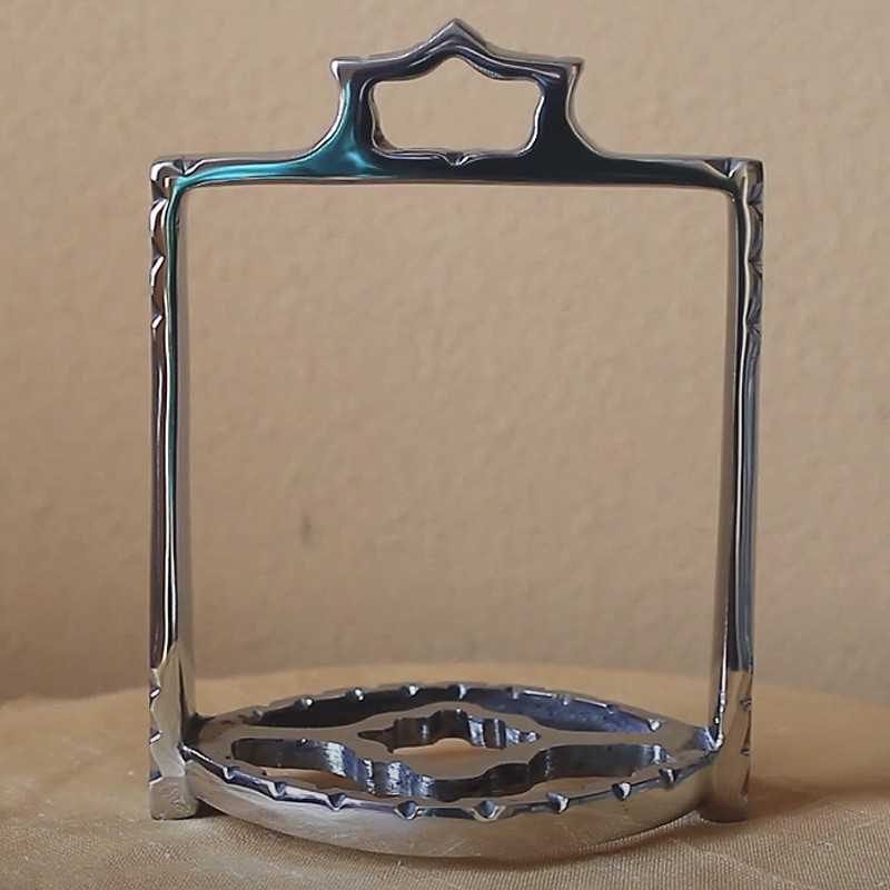 Suporte metálico prateado quadrado com base redonda em superfície bege